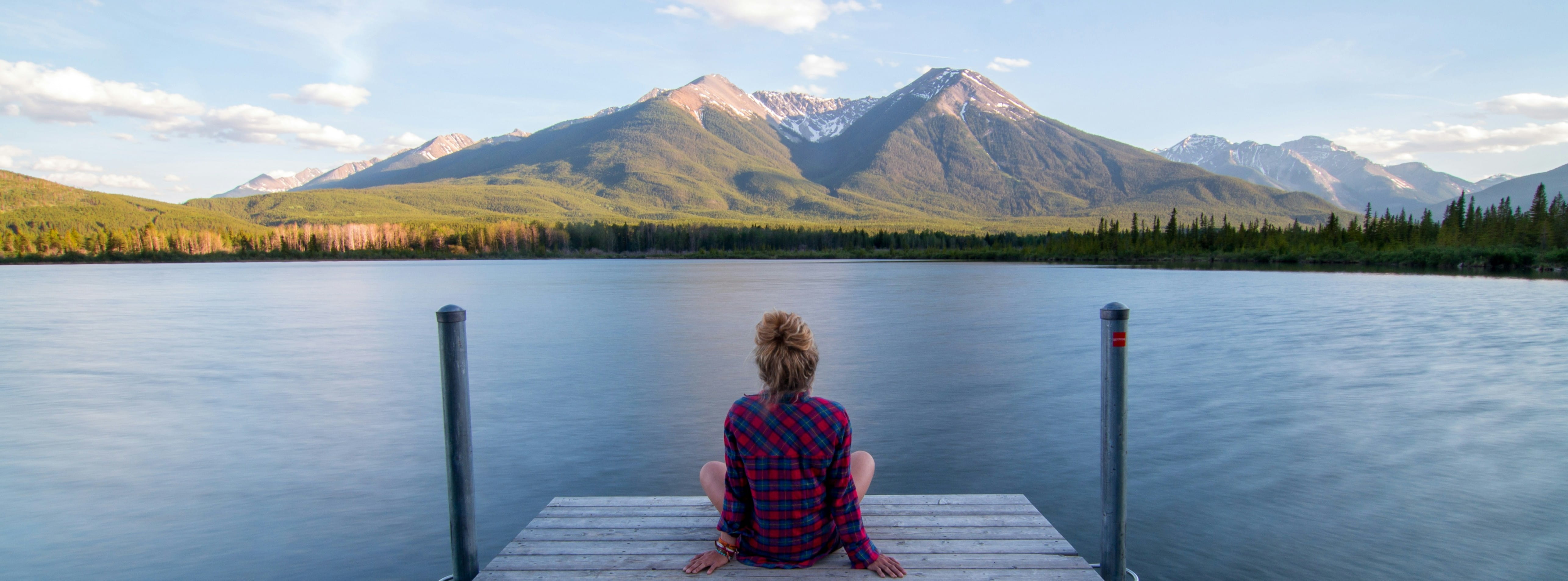 Personne assise face à un lac et aux montagnes, illustrant la réflexion, la confidentialité et la sérénité liées à une démarche de dépistage des IST.